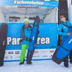 Gruppe mit Skitaschen und Snowbags vor Buehne