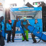 Gruppe mit Skitaschen und Snowbags vor Buehne